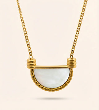 Gold necklace with a semi-circular pendant on a light beige background