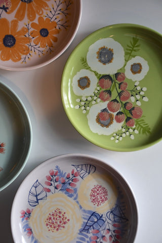 Set of colorful ceramic plates with floral designs on a white surface