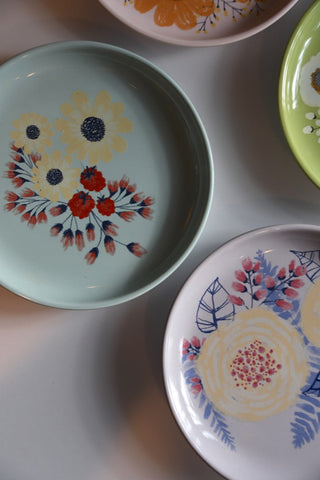 Set of decorative plates with floral patterns on a light gray surface