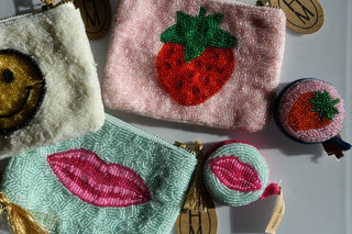 Collection of embroidered pouches with various designs on a white background