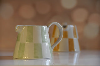 Green and white striped ceramic pitcher on a blurred background