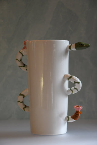 White ceramic vase with snake handles and a flower on a gray background