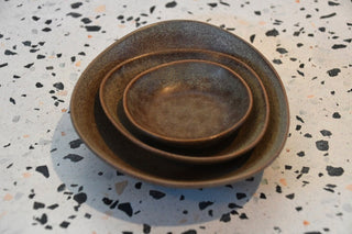 Set of three ceramic bowls stacked on a speckled surface