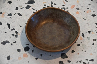 Brown ceramic bowl on a speckled countertop