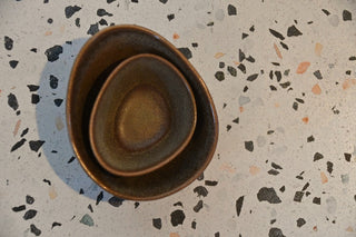 Three ceramic bowls stacked on a terrazzo countertop