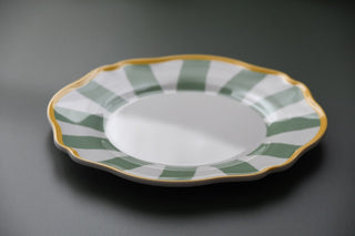 Ceramic plate with green and gold decorative rim on a gray background