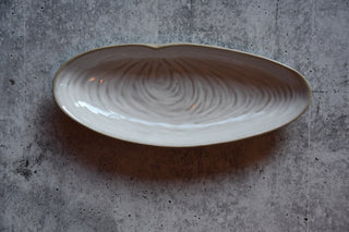 Ceramic dish with wavy pattern on a gray concrete surface
