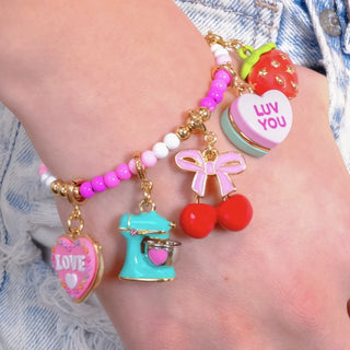 Colorful bracelet with various charms on a wrist against a denim background