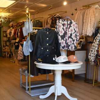 Interior of a store with clothing on display around a small round table.