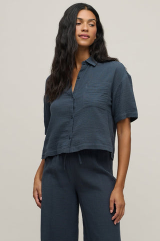 Woman wearing a dark blue shirt and pants against a plain background