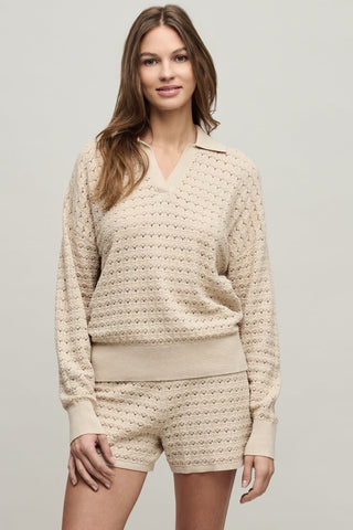 Woman wearing a beige knitted sweater and shorts set on a plain background