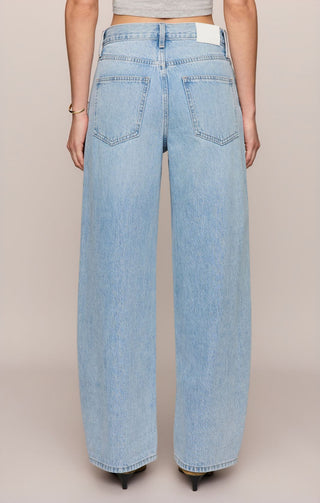 Light blue jeans worn by a person on a beige background