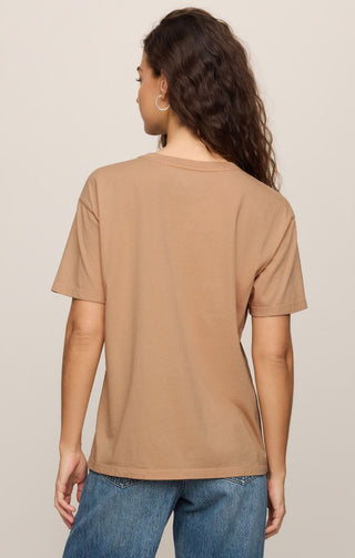 Person wearing a brown t-shirt and blue jeans on a beige background