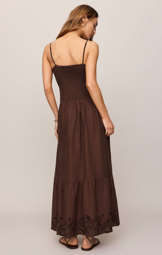 Woman wearing a brown dress with thin straps on a plain background