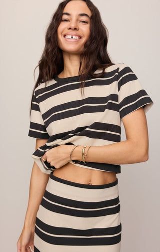 Woman wearing a black and beige striped outfit against a plain background