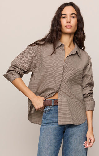 Woman wearing a brown checkered shirt and blue jeans on a beige background