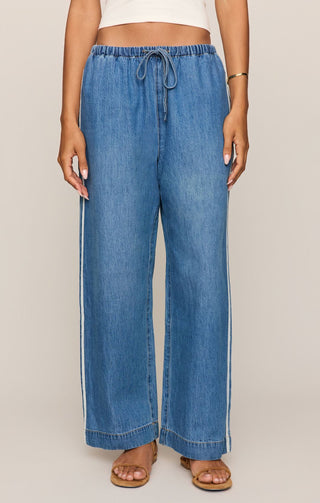 Person wearing blue denim wide-leg pants on a plain background
