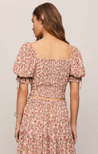 Woman wearing a floral dress with puff sleeves on a plain background