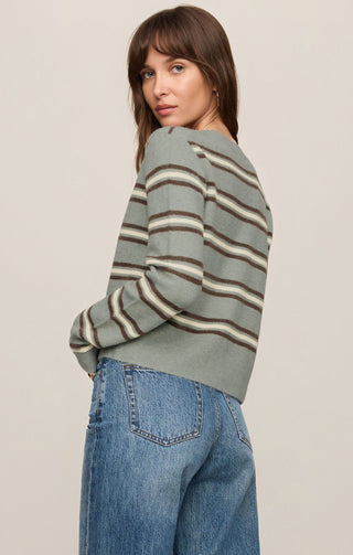 Woman wearing a striped sweater and jeans against a plain background