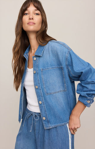 Woman wearing a blue denim jacket and pants on a plain background