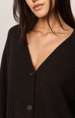 Close-up of a model wearing a dark brown V-neck button-up cardigan sweater.
