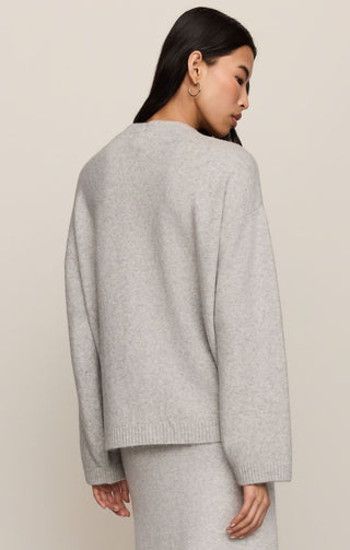 Person wearing a gray sweater against a beige background