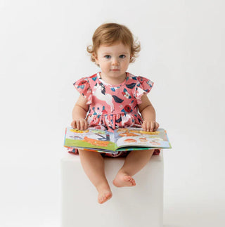 Child in a floral dress holding an open book on a white background