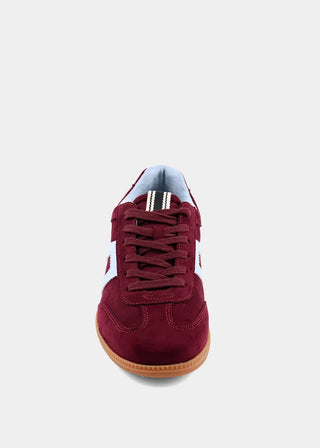 A single low-top sneaker shown from a front-facing perspective against a light gray background. The shoe features a burgundy suede upper, matching burgundy laces, a white side stripe detail, and a gum brown sole.