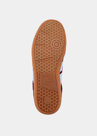 Top-down view of a shoe sole showing a brown gum rubber tread with a honeycomb pattern and a circular target logo embossed in the center, on a light gray background.