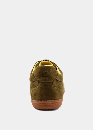 A single low-top sneaker shown from the back, featuring an olive green suede upper, a yellow interior lining, and a brown gum sole, set against a plain light gray background.
