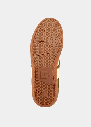 The outsole of a shoe in a light beige and olive green colorway, featuring a prominent brown honeycomb tread pattern and a 'SHU SHOP' logo embossed on the heel.