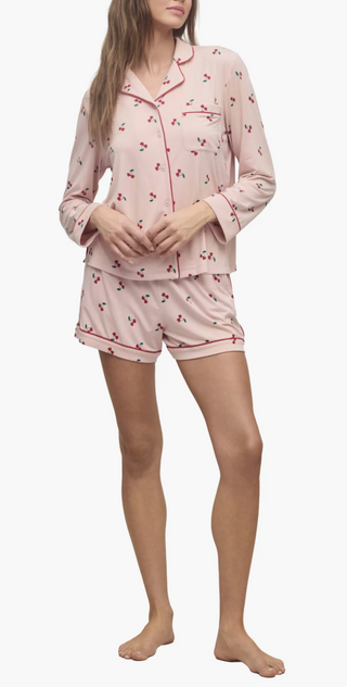 Woman wearing a pink pajama set with cherry pattern on a white background