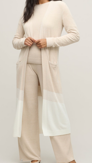 Person wearing a beige long-sleeve top and pants on a white background