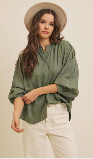 Woman wearing a green shirt and beige hat on a plain background
