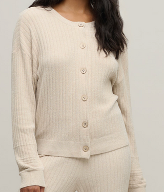 Person wearing a beige ribbed cardigan on a plain background