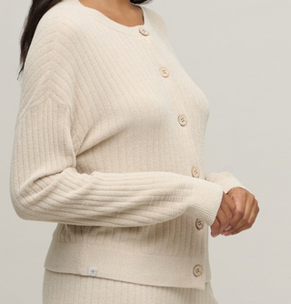 Beige ribbed sweater with button details on a plain background