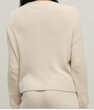 Beige ribbed sweater worn by a person on a plain background