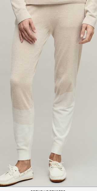Beige jogger pants worn with white sneakers on a plain background