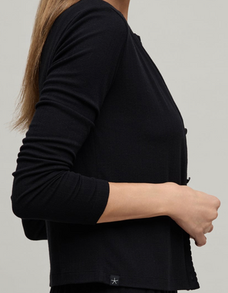 Person wearing a black long-sleeve top on a plain background