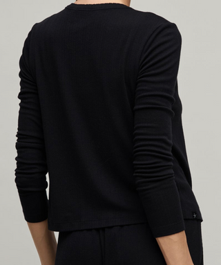 Black long-sleeve shirt worn by a person on a gray background