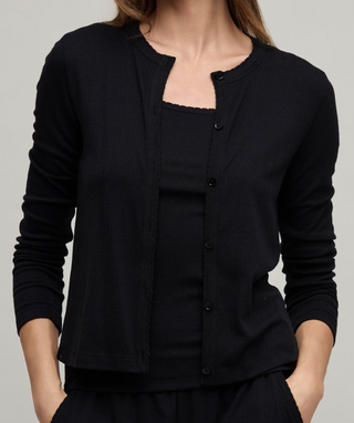 Person wearing a black cardigan over a black top on a plain background