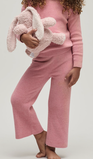 Child wearing pink pajamas holding a plush toy against a white background