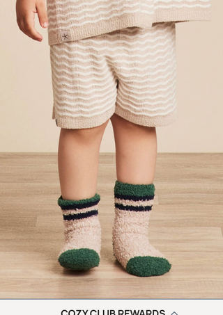 Child wearing striped socks with a neutral background