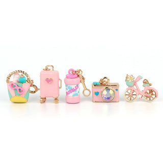 Set of colorful keychains including a cup, pink bag, bubblegum-themed bottle, camera, and bicycle on a white background.