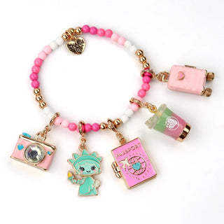 A beaded charm bracelet with pink, white, and gold beads, featuring five dangling charms: a pink camera, a mint green cartoon character, a pink passport, a green drink cup, and a gold heart charm.