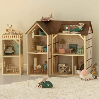 Wooden dollhouse with furniture and toys on a soft surface