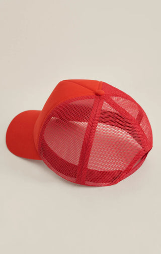 Red baseball cap with mesh back on a beige background