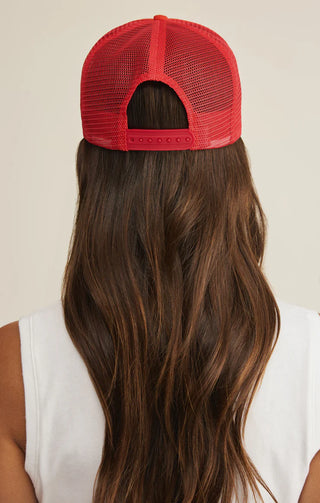 Red mesh cap worn by a person with long hair on a plain background