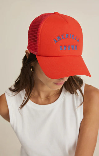 Person wearing a red cap with 'America Grown' text on a neutral background