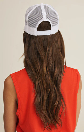 Person wearing a white mesh cap and red sleeveless top on a beige background